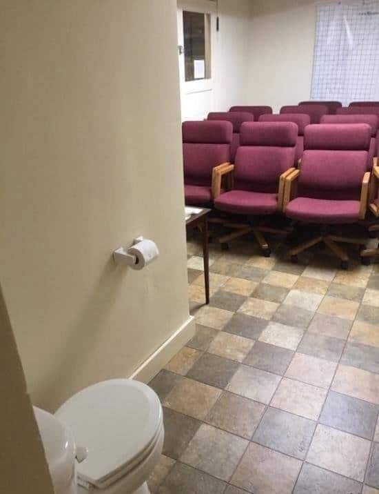 A toilet seat in front of many chairs